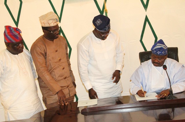 Governor Ajimobi signing the new bill into law.