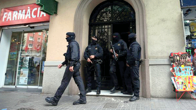 Spanish police stand guard outside an apartment building during a sweeping operation at some 12 locations [Photo Credit: The Express Tribune]
