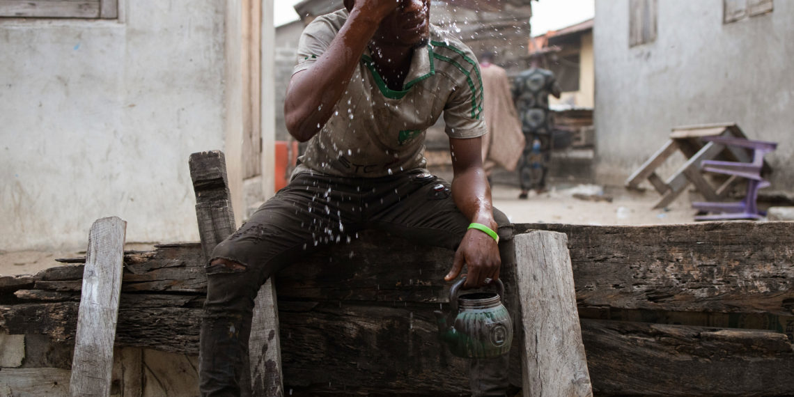 A Sagbo Kodji man takes an early morning wash using well water. Because well water is not clean, it has to be left for the dirt in it to settle before it can be used. [PHOTO CREDIT: Nengi Nelson]