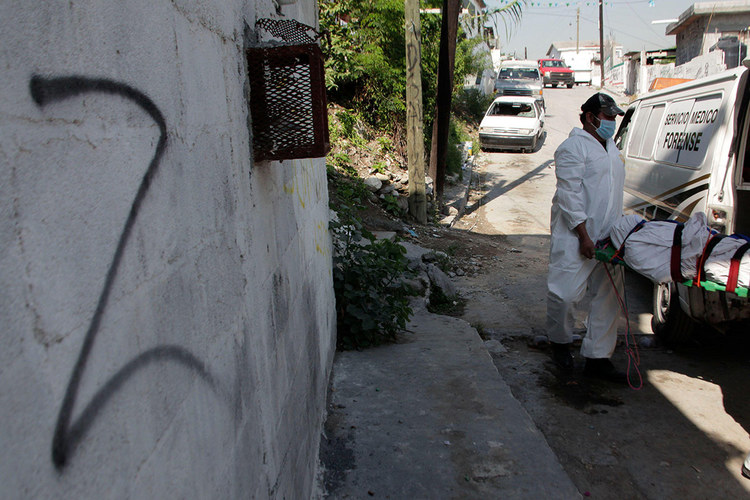 Forensic technicians remove a body from a crime scene near a wall spray painted with the “Z” symbol of the Zetas drug cartel, in Monterrey, Mexico, September 18, 2012. [Credit: REUTERS/Daniel Becerril ]