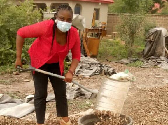 Joy Itamah gathering peels of cassava for processing.