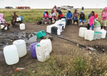 Residents of a new informal settlement outside Winburg gather to fill containers with water from a pipe supplied by the municipality. Sana Ntho, 54, said the water either has to be boiled or disinfected before drinking. With no electricity available, and firewood a scarce commodity, she adds a spoon of bleach to every 20-liter bucket of water.