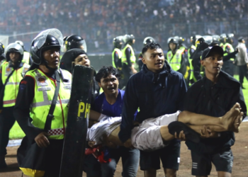 Fans carry an injured man following clashes during a football match at Kanjuruhan Stadium in Malang, East Java, Indonesia [Yudha Prabowo/AP Photo]