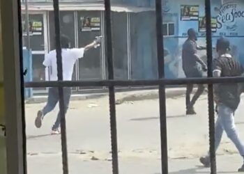 One of thugs, (the one with a white polo) pointing and shooting a gun.